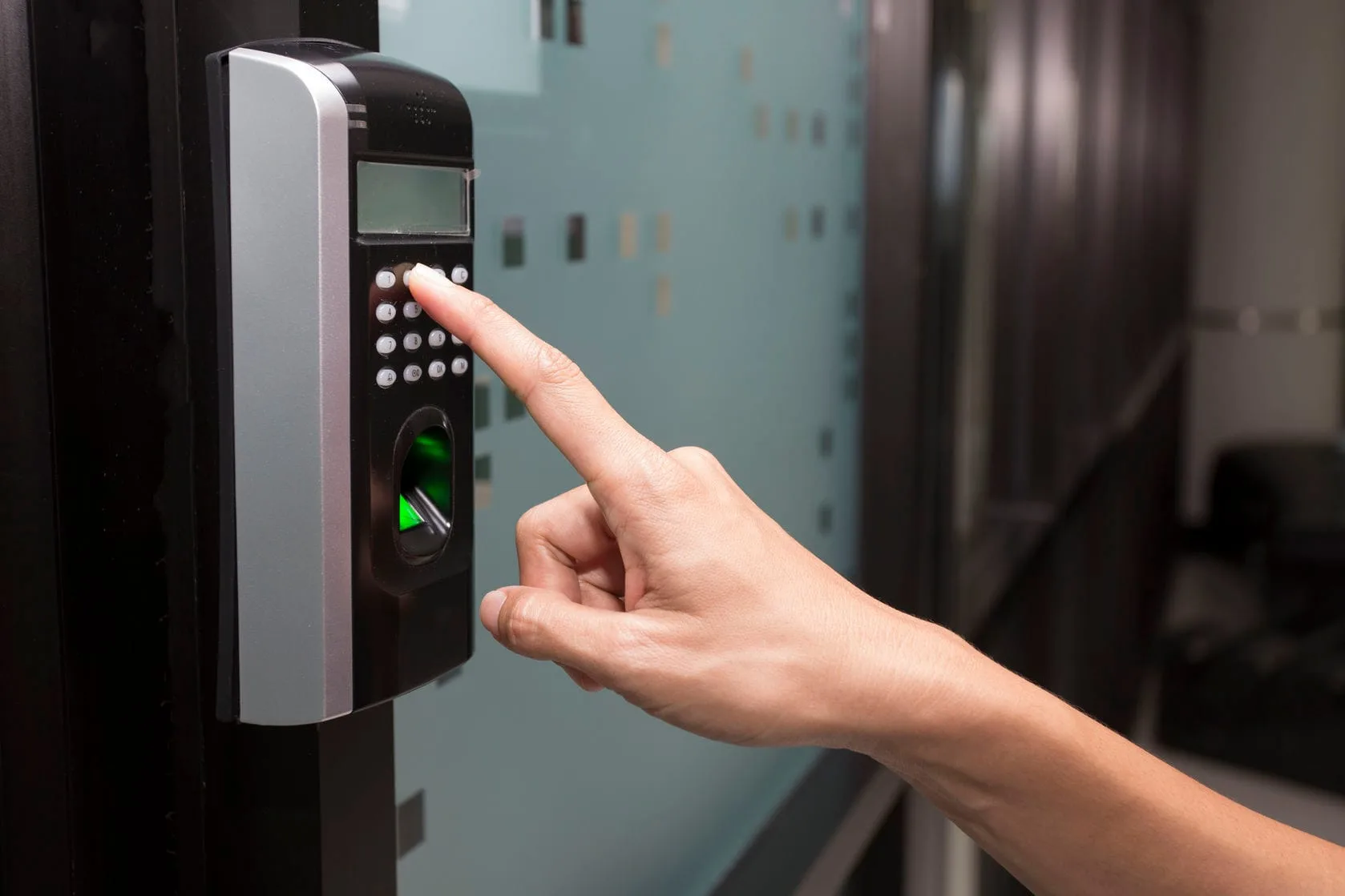 Lector biométrico de control de acceso con teclado, instalado en la puerta de una oficina